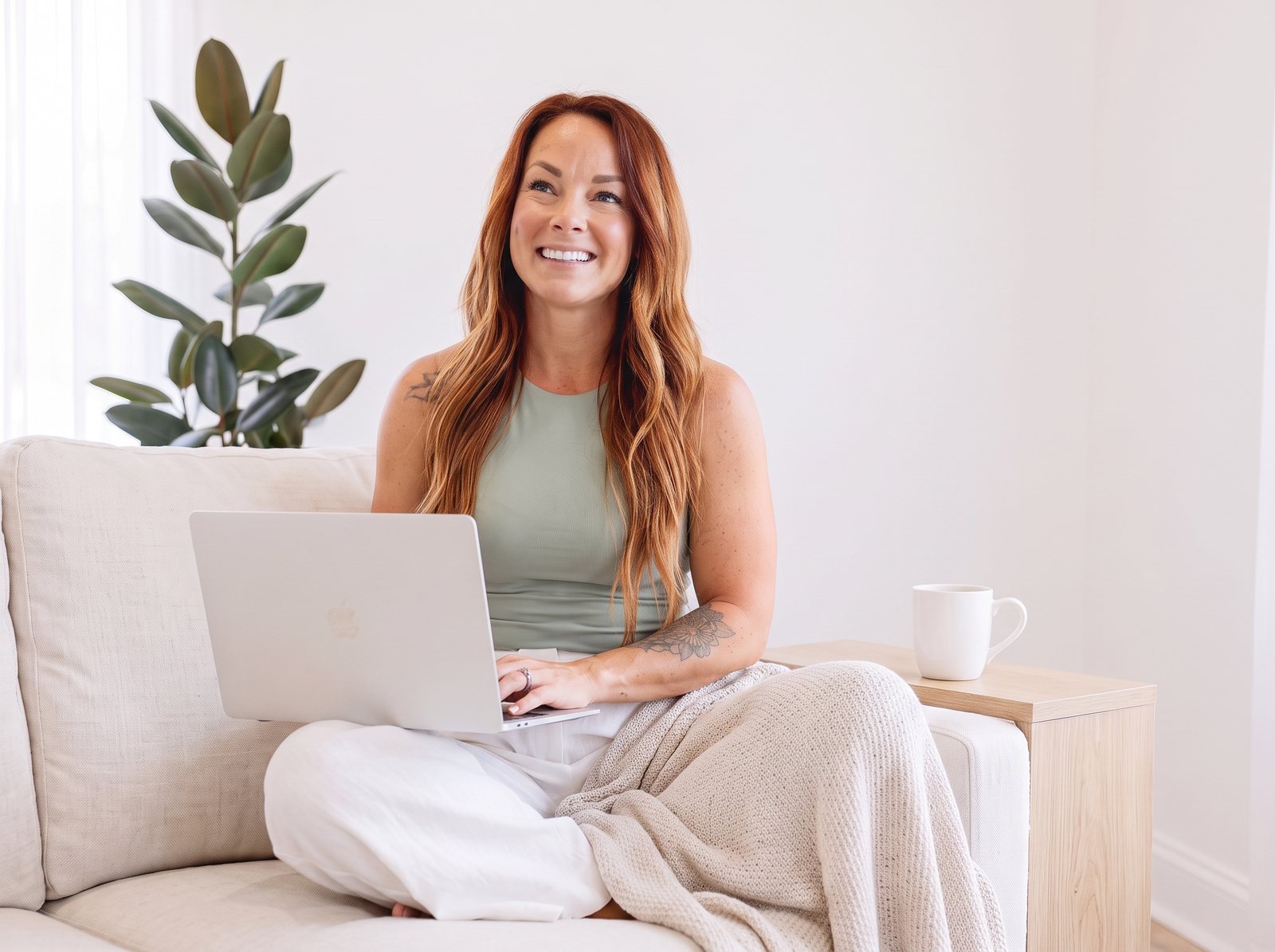 Ashley smiling on her couch with her laptop