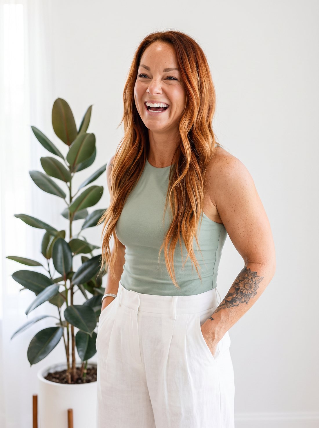 Ashley laughing in a sage tank beside a plant