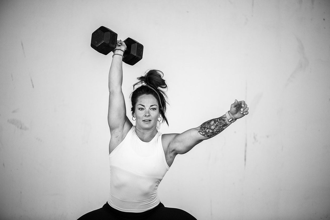 Ashley pressing a dumbbell overhead, black and white